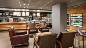 A modern cafe with leather seating, a coffee bar, and a display of beverages.