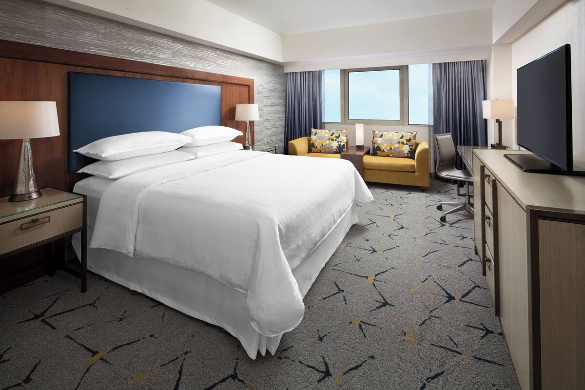 Une chambre d’hôtel avec un grand lit, un canapé, un bureau et une télévision.