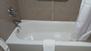 Une baignoire blanche avec un rideau de douche, une serviette et un robinet chromé.