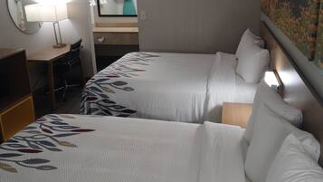 A hotel room with two beds, a desk, a chair, and a mirror.