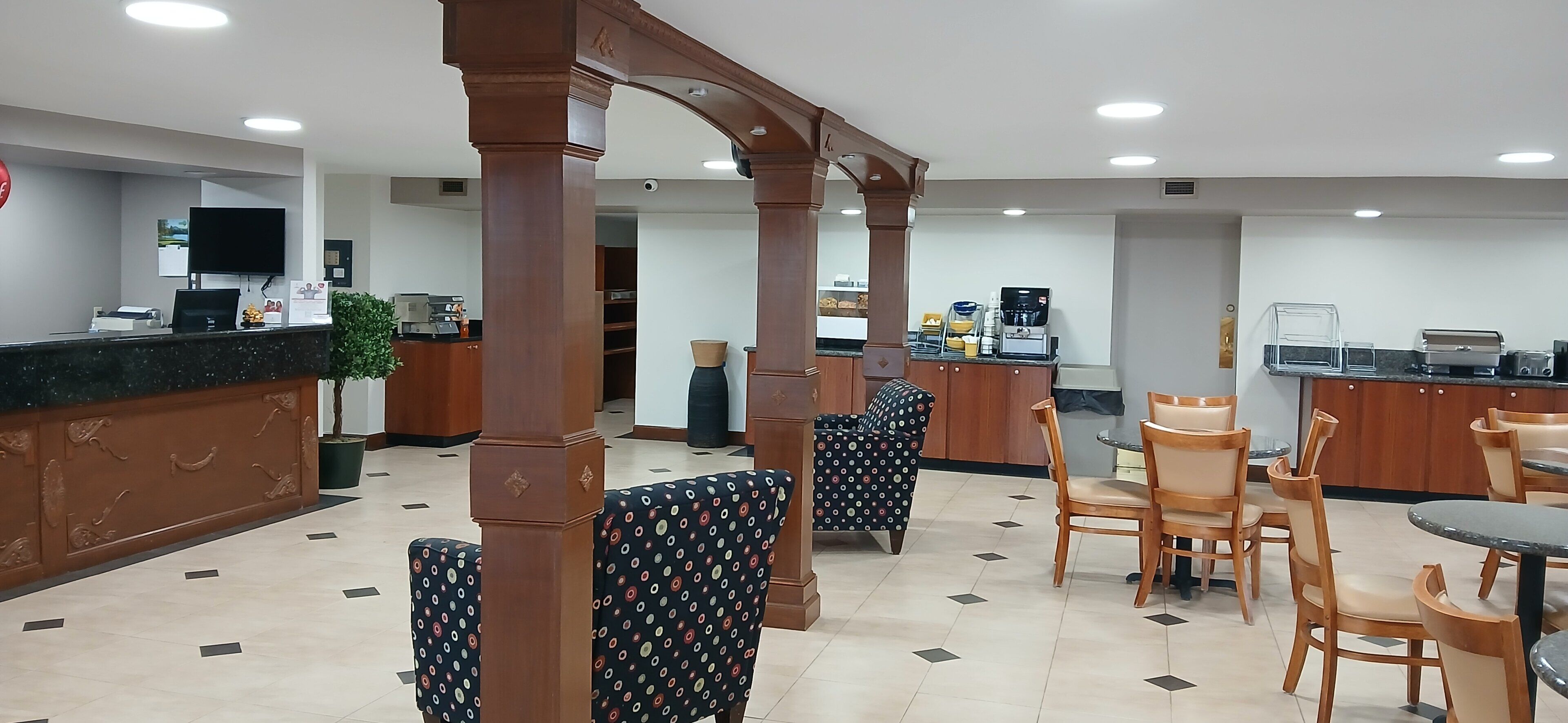 A hotel lobby with a reception desk, seating area, and coffee machines.