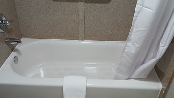 Una bañera blanca con cortina de ducha, una toalla y un grifo de cromo.