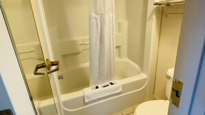 A bathroom with a bathtub, shower curtain, toilet, and a towel rack.
