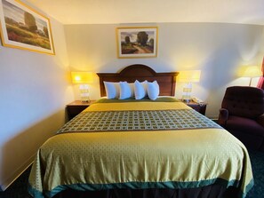 Relax in a cozy space with a neatly made bed, wooden headboard, and comfortable chair.