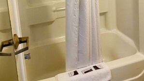 A bathroom with a bathtub, a shower curtain, and a towel rack with a towel.