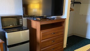 A kitchenette with a microwave, refrigerator, and a flat-screen TV on a wooden cabinet.