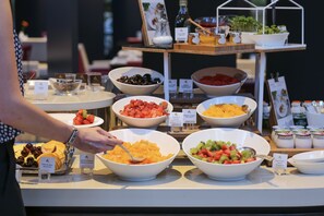 A buffet with various bowls of fruit and a person serving food. - Le Royal Hotels & Resorts (Luxembourg City)