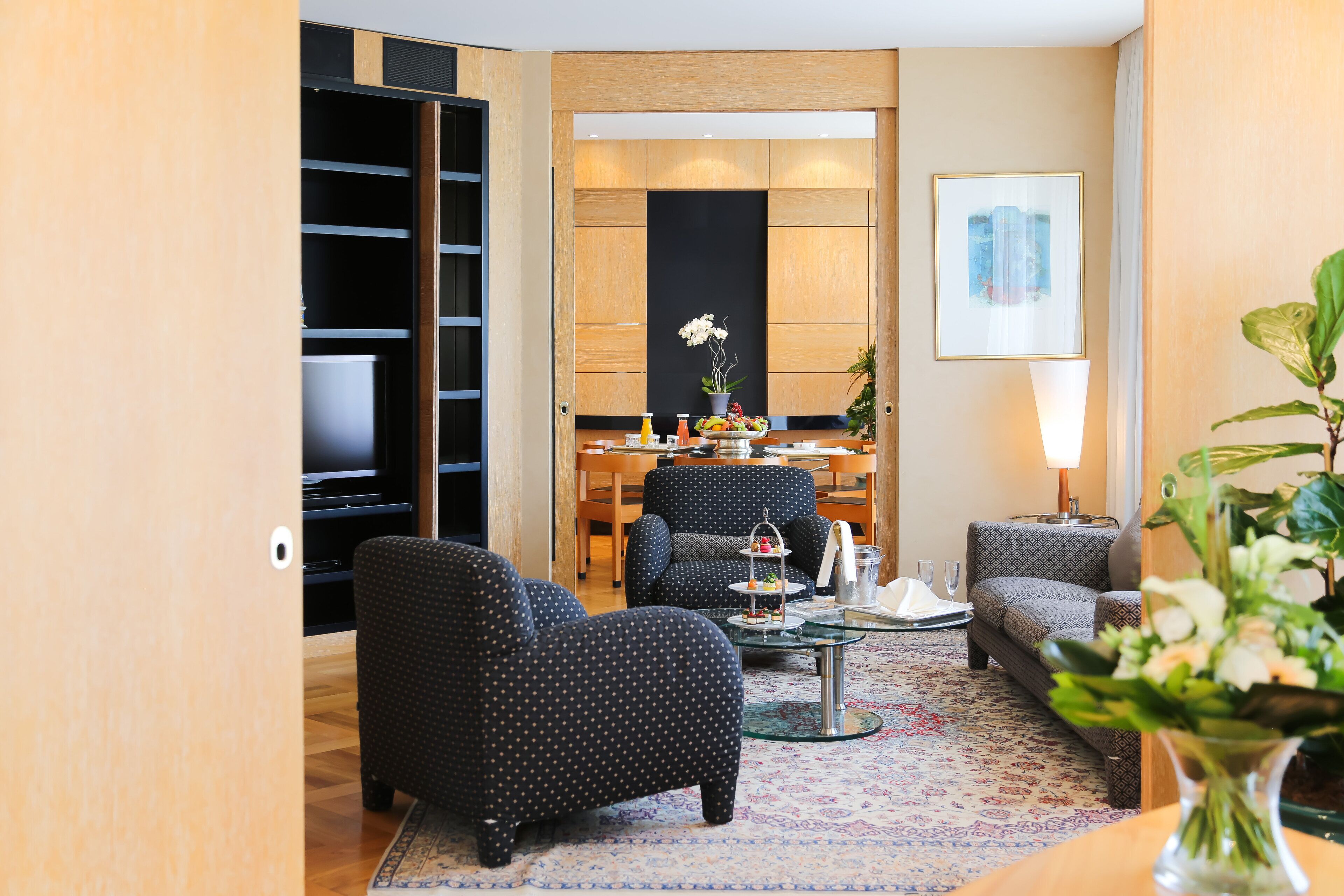A modern living room with a sofa, armchairs, a coffee table, and a dining area with a table and chairs.