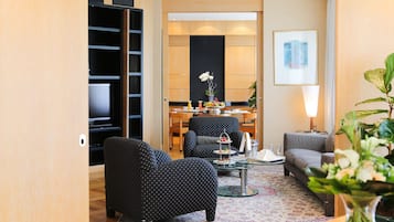A modern living room with a sofa, armchairs, a coffee table, and a dining area with a table and chairs.