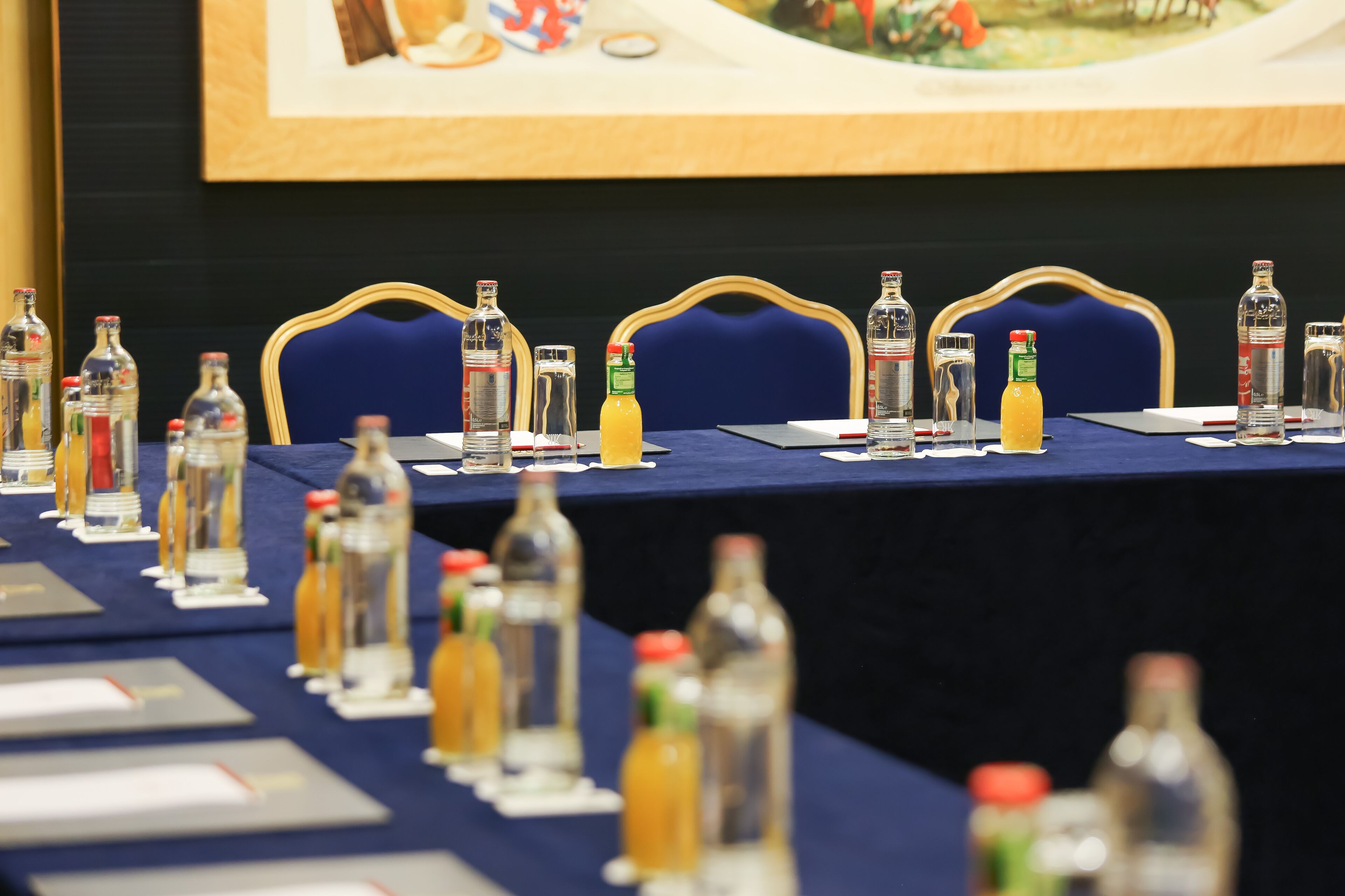 Un tavolo da conferenza con sedie, bottiglie d'acqua e cartellini con i nomi.