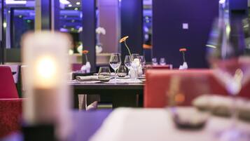A restaurant interior with tables set for dining, featuring clear glassware and a candle centerpiece.