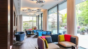 A modern hotel lobby with a large seating area, large windows, and a view of the outdoors.