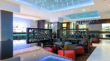 A modern hotel lobby with a bar area, seating arrangements, and decorative lighting.