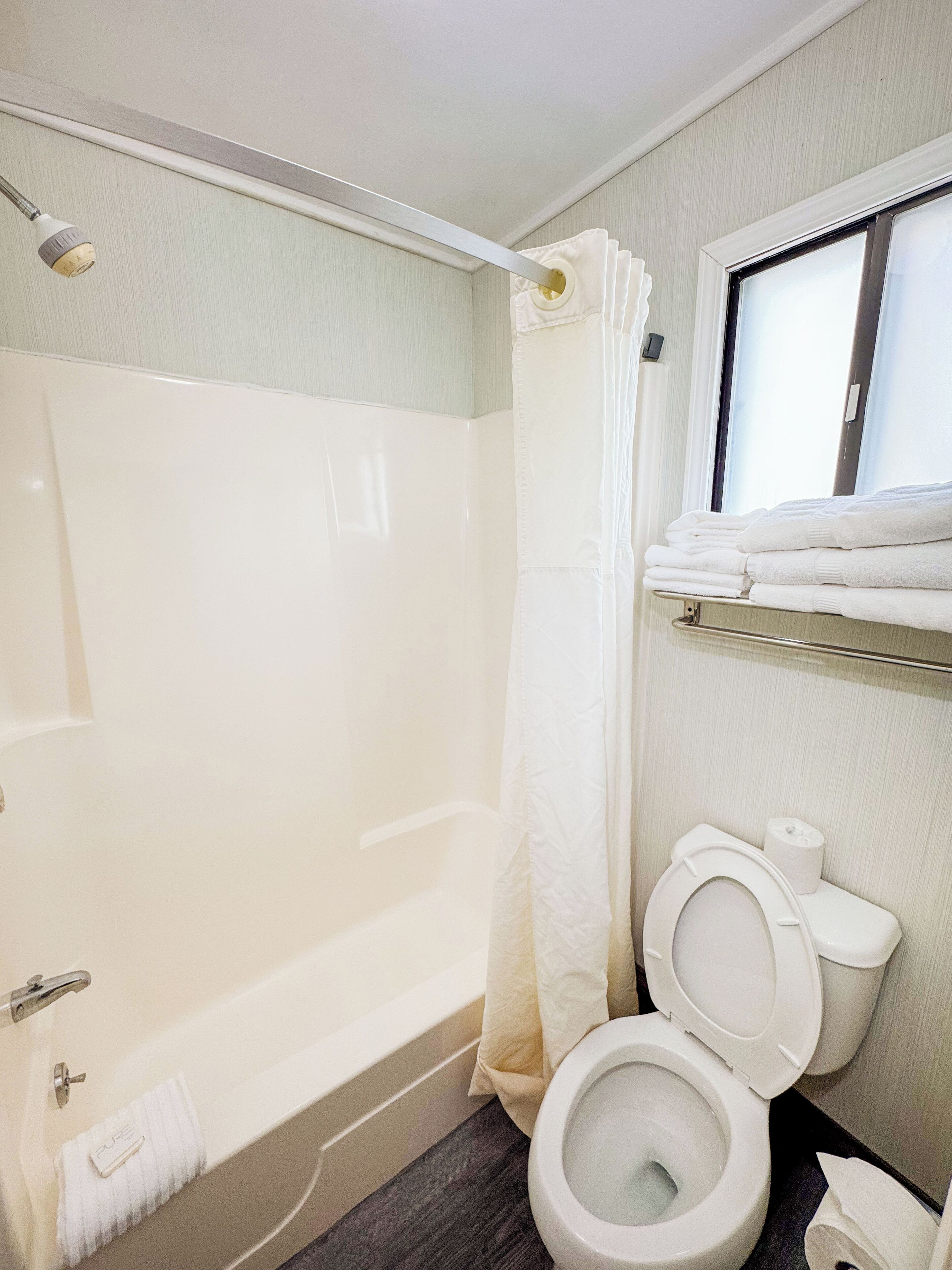 Een badkamer met een bad, toilet en douchegordijn.