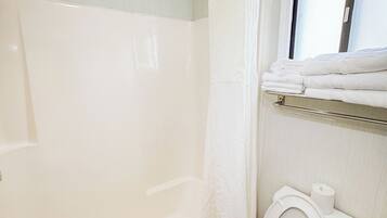 Een badkamer met een bad, toilet en douchegordijn.