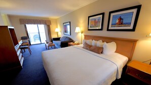 Ein Hotelzimmer mit einem großen Bett, einem Schreibtisch, einem Stuhl, einem Kleiderschrank und einem Balkon.