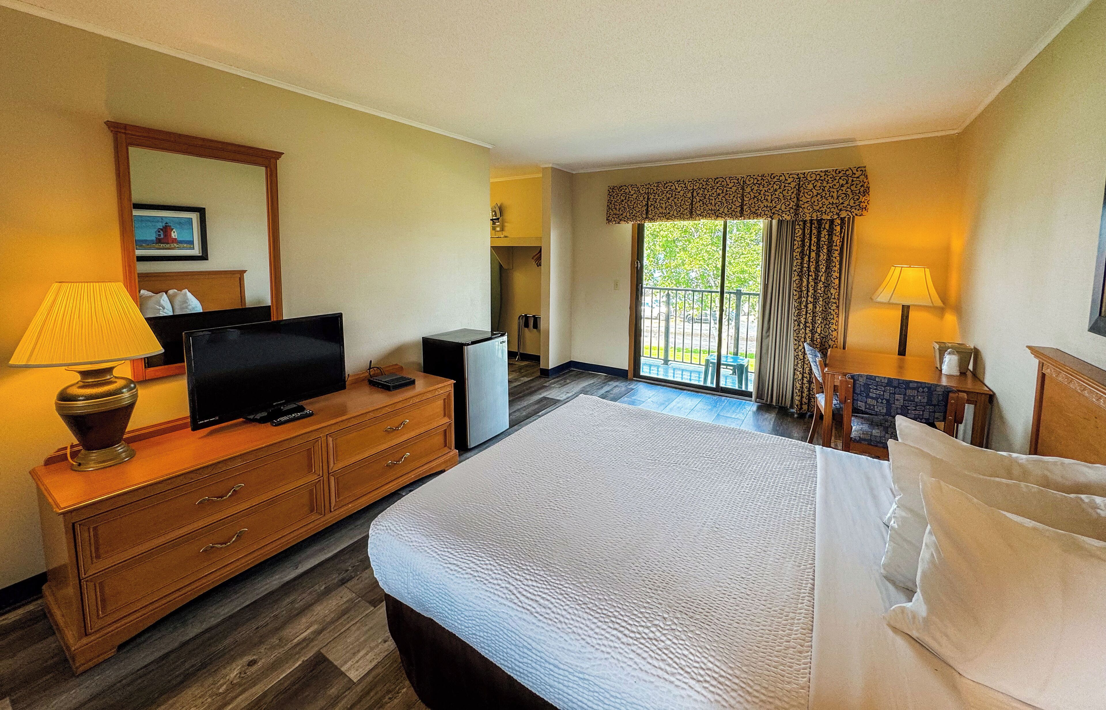 A hotel room with a bed, a television, a desk, and a chair.