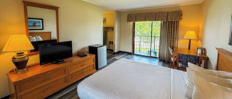 Una habitación de hotel con una cama, televisión, escritorio y una silla.
