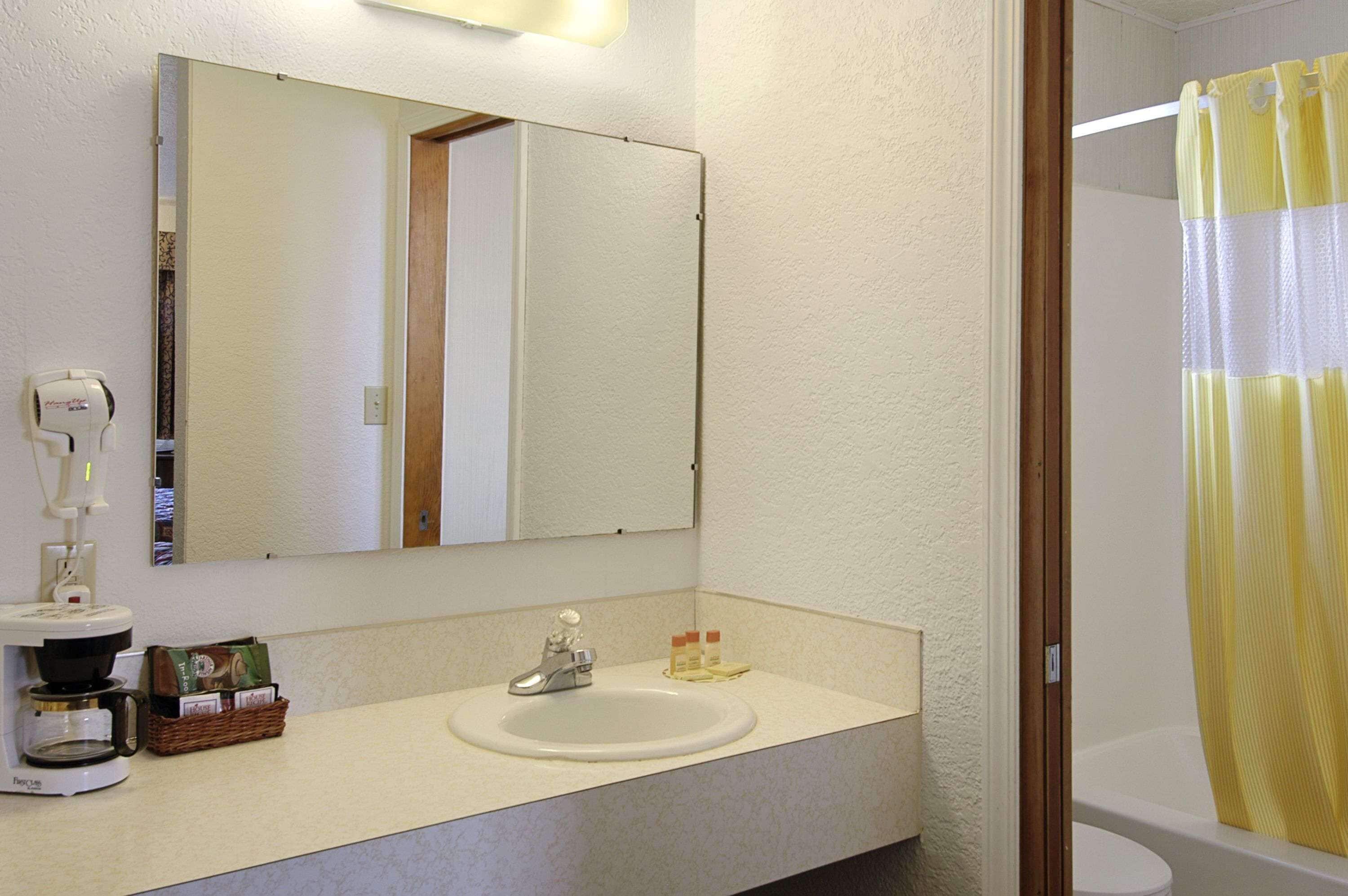 A bathroom with a sink, mirror, and shower curtain.