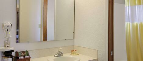 A bathroom with a sink, mirror, and shower curtain.