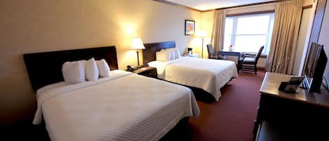 Habitación de hotel con dos camas, un escritorio y una silla.