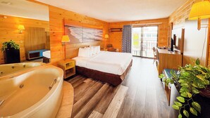 Ein Hotelzimmer mit einem großen Bett, einer Badewanne, einem Schreibtisch mit Computer sowie einem Balkon mit Stühlen.