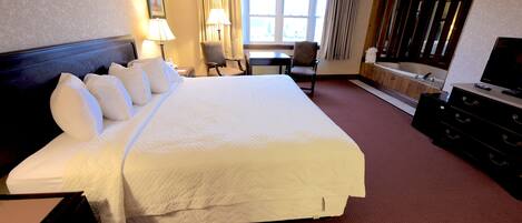 Een hotelkamer met een groot bed, een bureau, een stoel, een televisie en een bad.