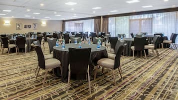 A conference room with round tables, chairs, and water bottles.
