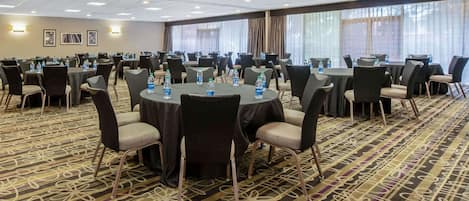 Une salle de conférence équipée de tables rondes, de chaises et de bouteilles d’eau.