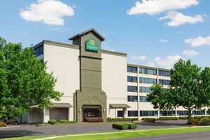 Un moderno edificio de hotel con un letrero llamativo, varios pisos y un césped cuidado.