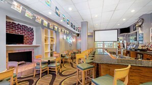 A hotel lobby with a fireplace, bar area, and seating.