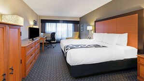 A hotel room with a large bed, a desk with a computer, a TV, and a wardrobe.