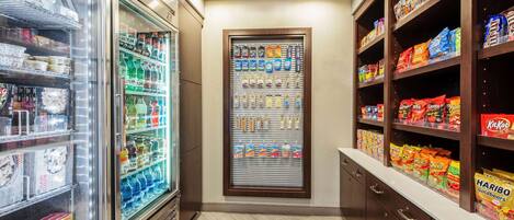 Una tienda de conveniencia con secciones refrigeradas, estantes de aperitivos y una exhibición de diversos productos.
