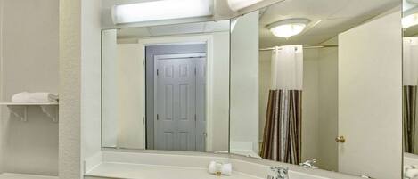 A bathroom with a white sink, a mirror, a shower curtain, and a door.