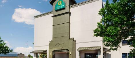 A La Quinta Inn & Suites building with a prominent entrance, a flagpole, and well-maintained landscaping.