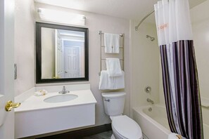 Chambre, 1 très grand lit, accessible aux personnes à mobilité réduite | Salle de bain | Ensemble baignoire-douche, articles de toilette (gratuits)