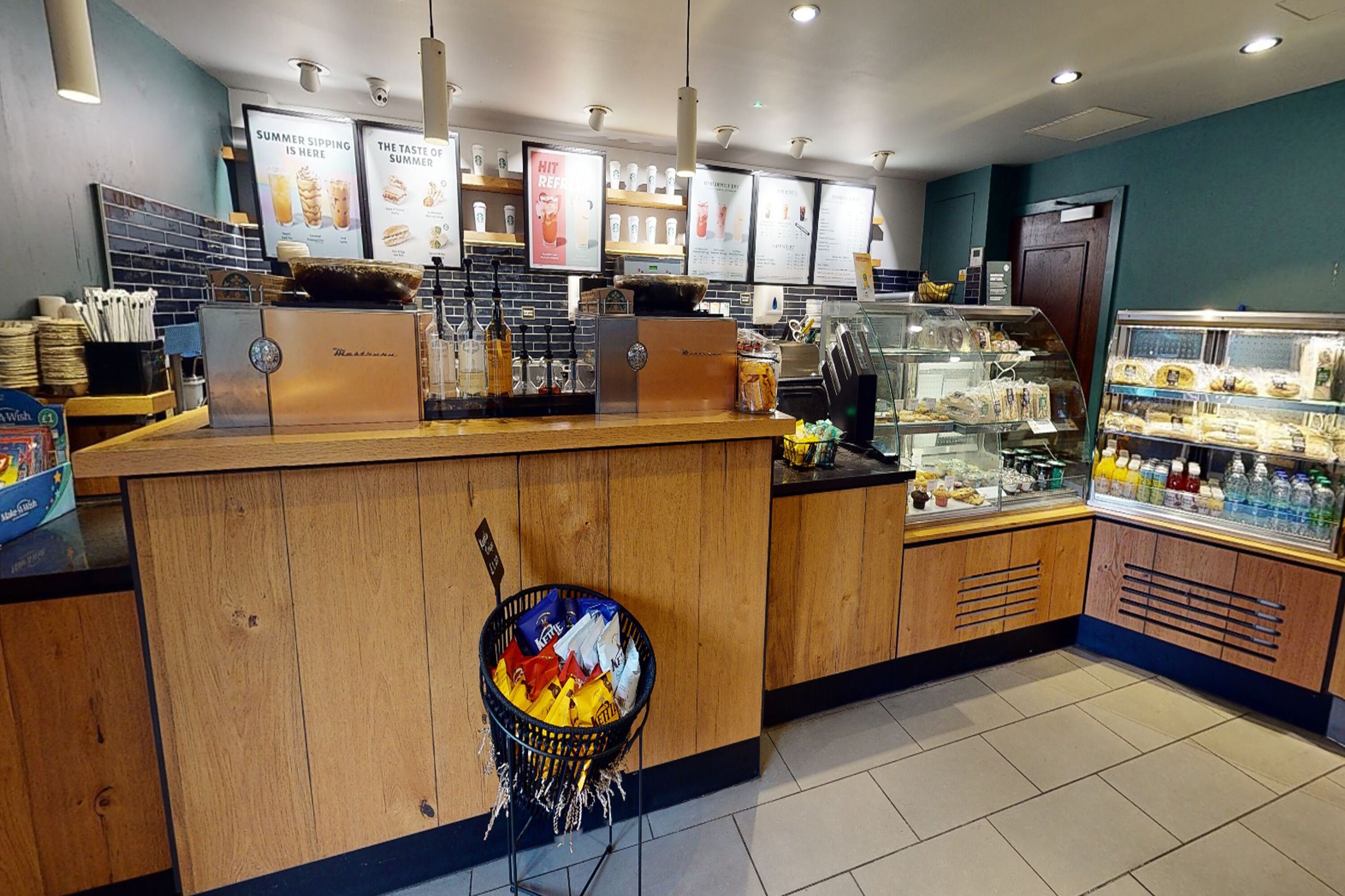 A bakery counter with a display of baked goods, a coffee machine, and a refrigerated display case.