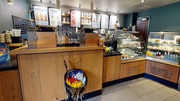 A bakery counter with a display of baked goods, a coffee machine, and a refrigerated display case.