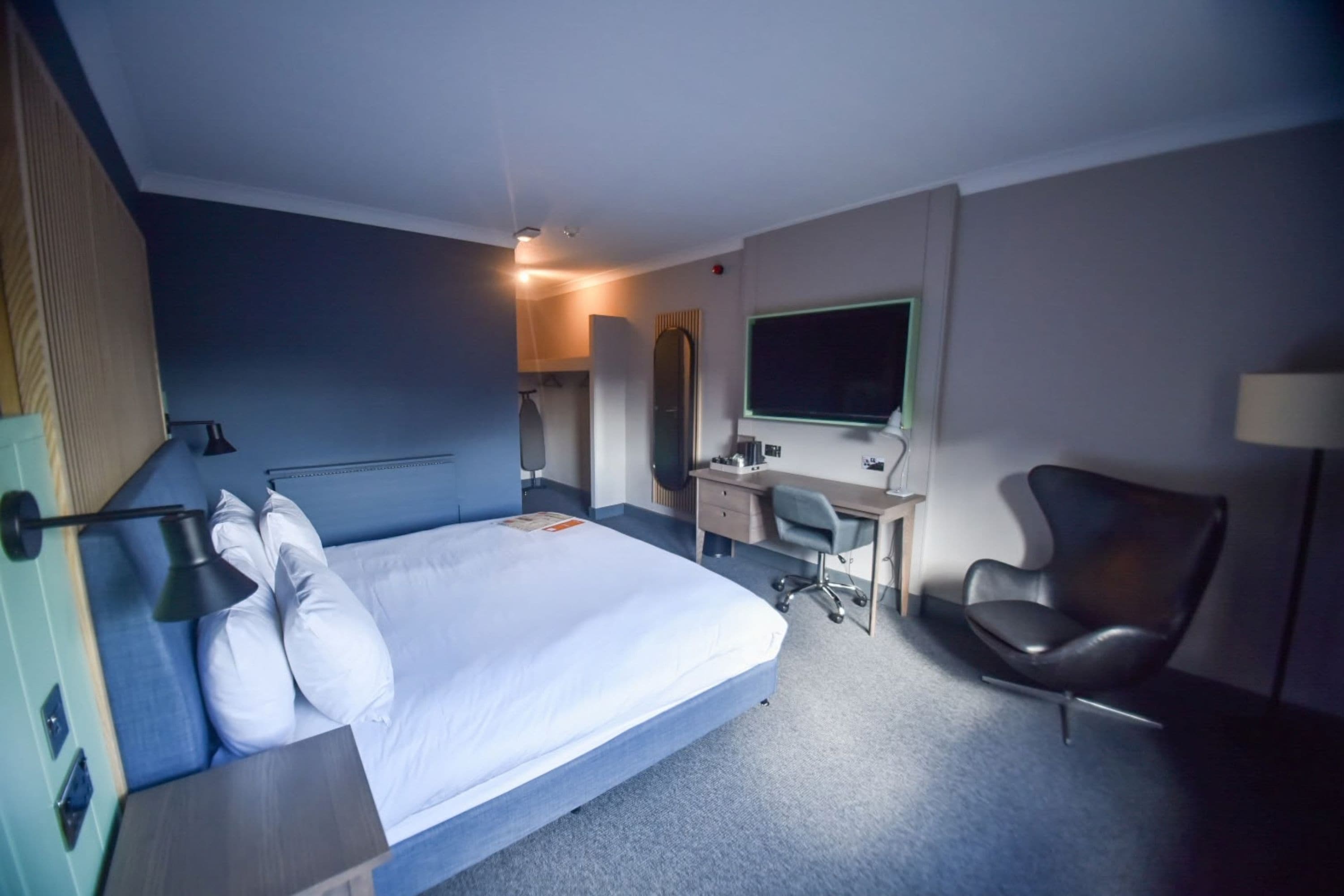 Ein Hotelzimmer mit Bett, Schreibtisch, Stuhl und Fernseher.