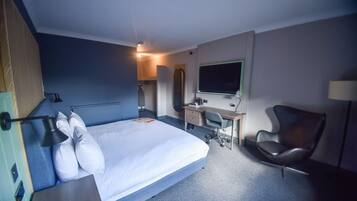 Ein Hotelzimmer mit Bett, Schreibtisch, Stuhl und Fernseher.