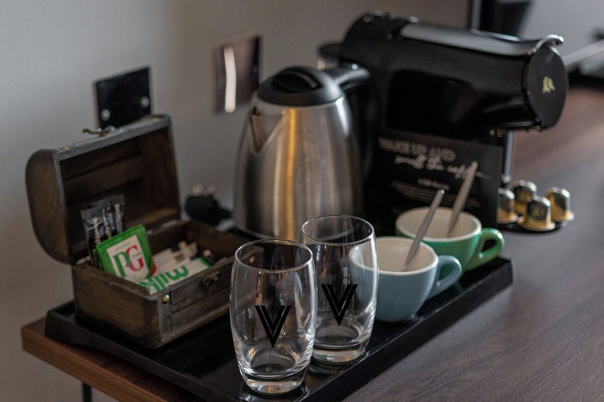 A tray with two glasses, a coffee pot, a box of PG cigarettes, and a mug on a wooden table.
