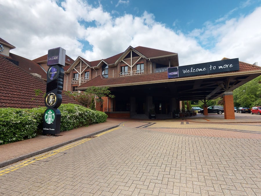 A hotel entrance with a covered walkway, a clock, and a Starbucks sign.
