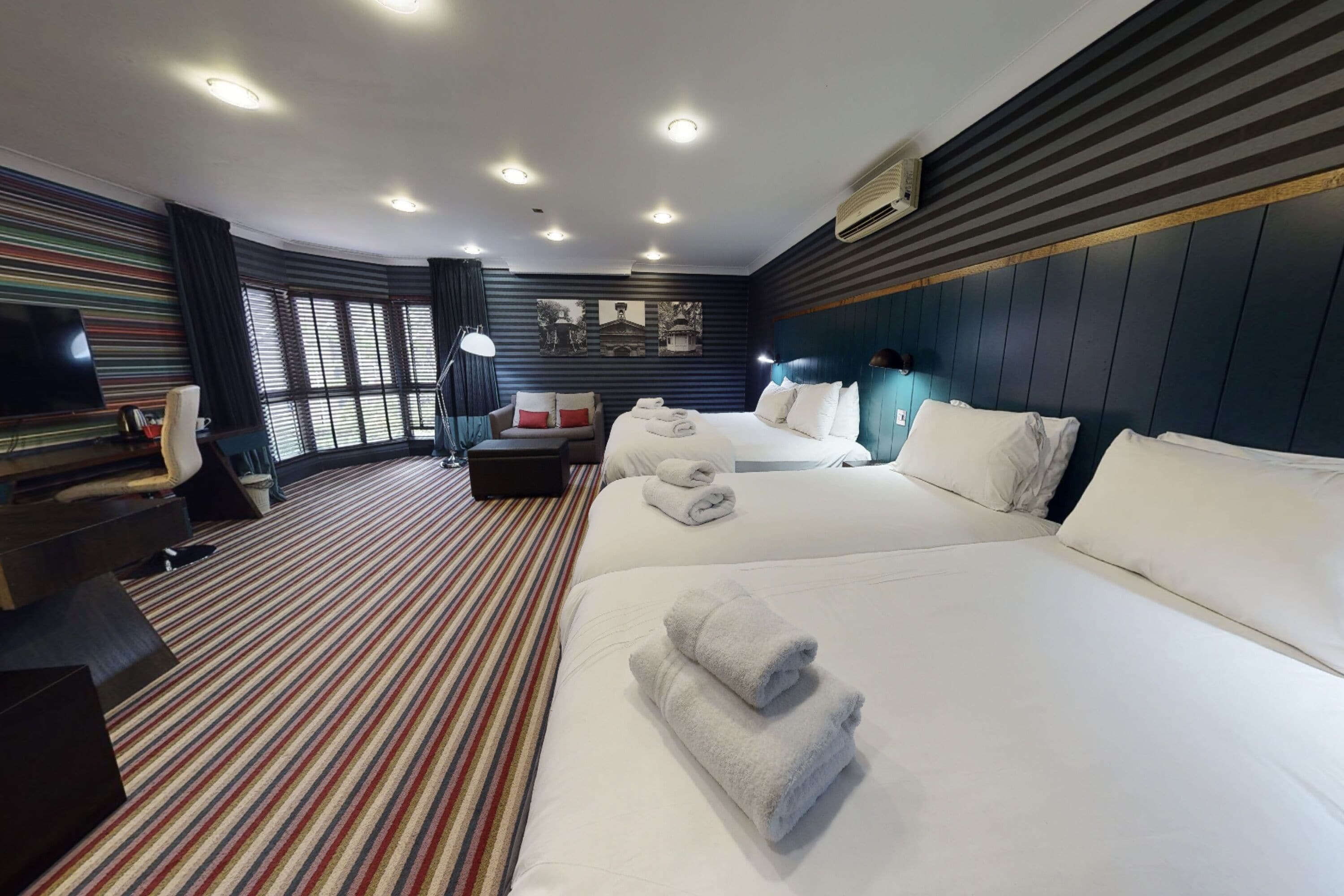 Une chambre d’hôtel avec un grand lit, un bureau, une télévision et une fenêtre avec des rideaux.