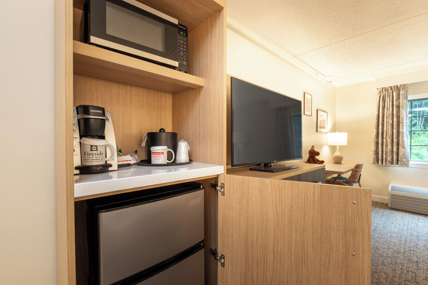 A compact kitchenette with a microwave, coffee maker, and a flat-screen TV.