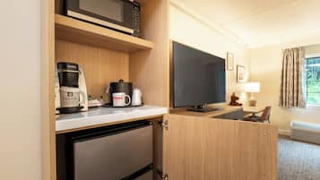 A compact kitchenette with a microwave, coffee maker, and a flat-screen TV.