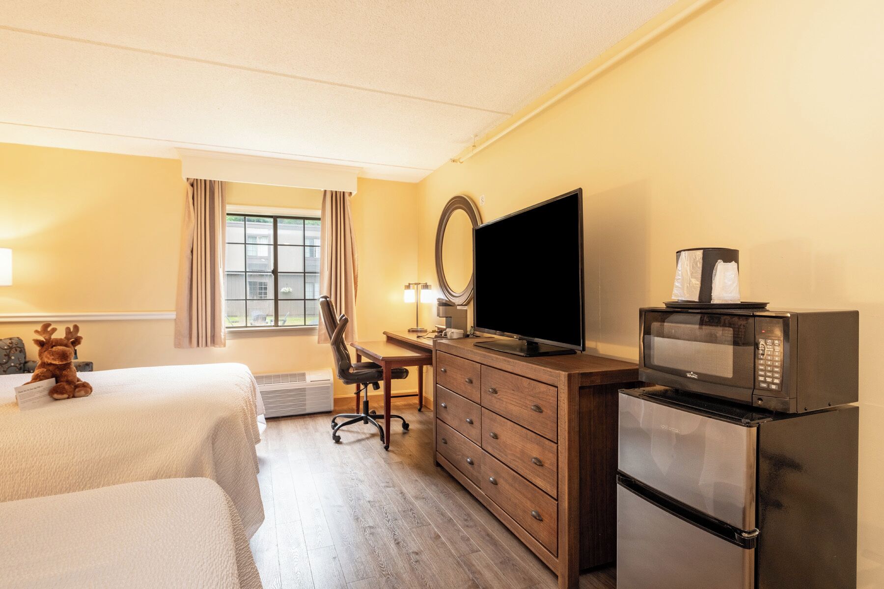 Una camera d'albergo con un letto, una scrivania con una sedia, una televisione, un forno a microonde e un frigorifero.