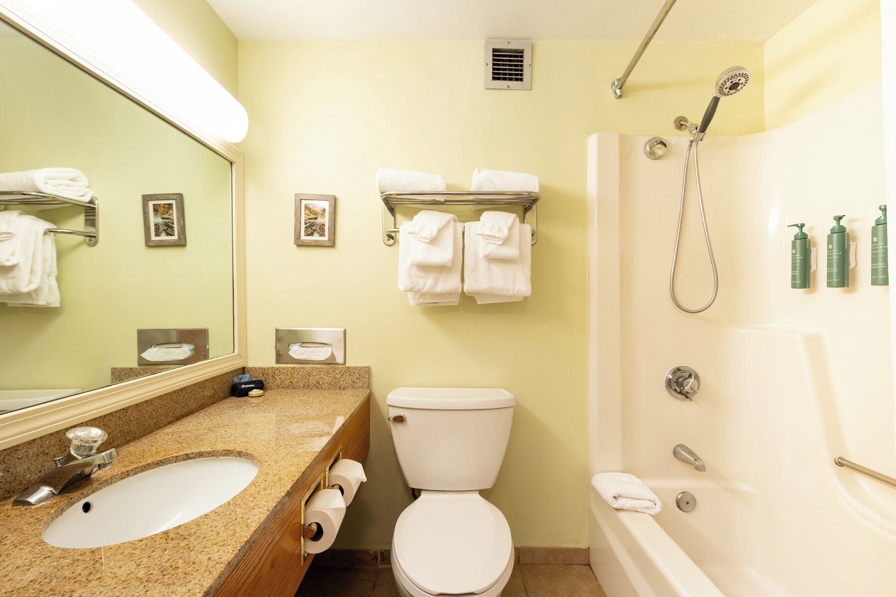 A bathroom with a sink, toilet, and shower. There are towels and toiletries on the wall.