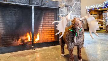 A moose statue with antlers in front of a fireplace with a fire.
