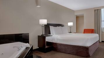 Una habitación de hotel con una cama grande, un baño independiente con bañera y una silla.