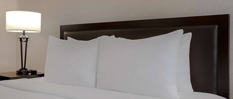 Una cama bien hecha con sábanas blancas y un cabecero oscuro.